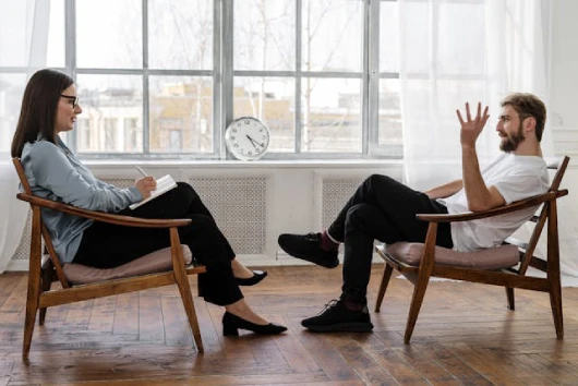 counseling-vs-therapy A man and woman in chairs, conversing about the differences between counseling and therapy in Singapore.