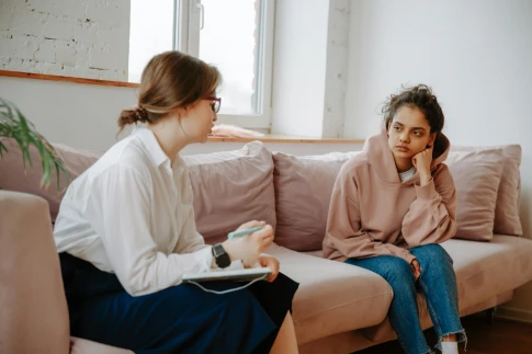 Two women engaged in conversation while sitting on a couch, representing counseling services in Singapore.