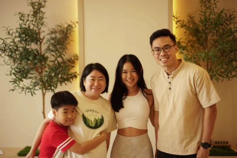 A family poses happily in front of a tree, representing connection and support, relevant to family counselling in Singapore.