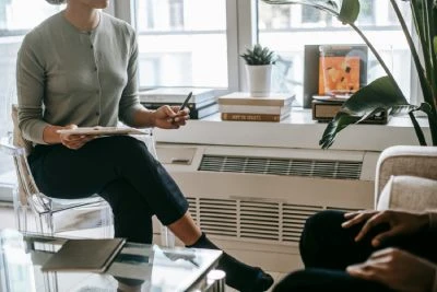 A woman speaks with a man in an office setting, discussing psychotherapy in Singapore.